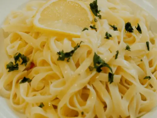 En tallrik med krämig citronpasta, toppad med en citronskiva och färsk persilja. Perfekt för en lätt lunch eller middag.