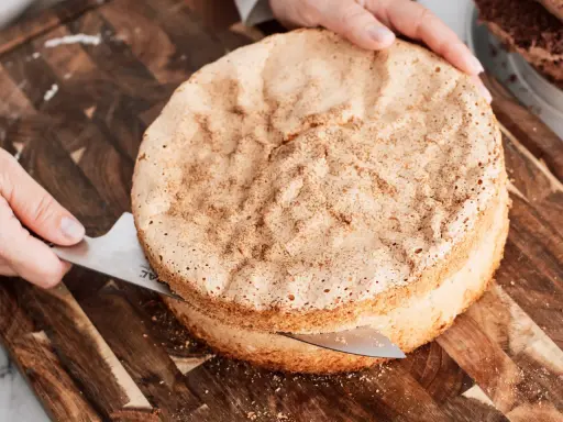 En person skär en fluffig tårtbotten med en kniv. Perfekt för ditt nästa tårta recept.
