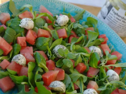 En uppfriskande sallad med vattenmelon, gröna blad och små bollar av ost, perfekt som sallad till paj.