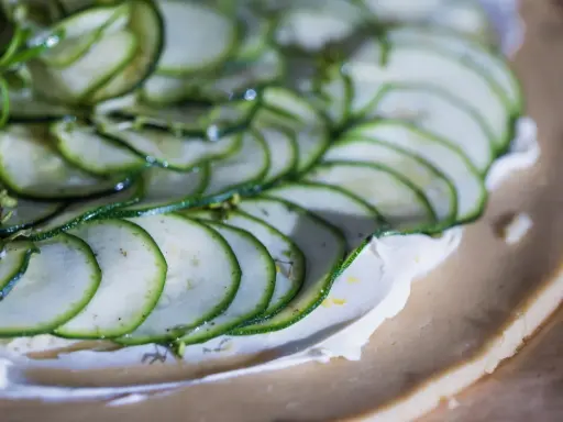 Tunna skivor av zucchini läggs på en krämig fyllning på en pajdeg. En underbart god paj som snart är redo att avnjutas.