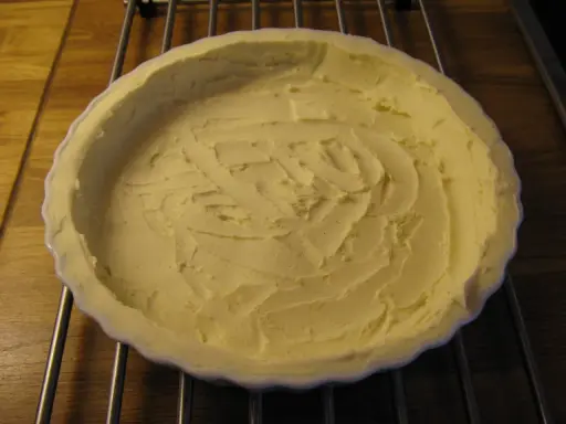 En vit pajform med en färdig glutenfri pajdeg från Lailas. Pajdegen är pressad mot formens kanter och har ett mönster i mitten.