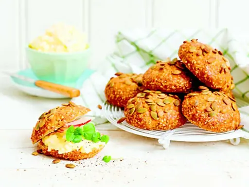 Frukost tips: Nybakade frallor med pumpafrön och sesamfrön, en fylld med äggsallad, skinka och basilika.