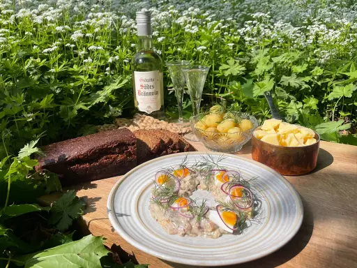 En härlig sommardukning med sill, färskpotatis, mörkt bröd och en flaska Östgöta Sades Brännvin för egen snaps till sillen.