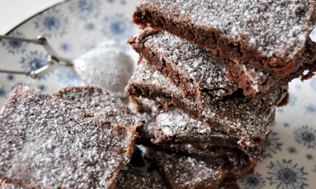 En hög med saftig kladdkaka i långpanna, pudrad med florsocker. Perfekt för fikat!