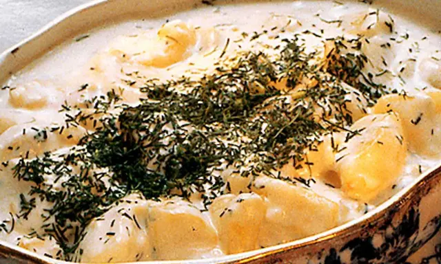 En krämig stuvad potatis med dill, serverad i ett vackert uppläggningsfat.