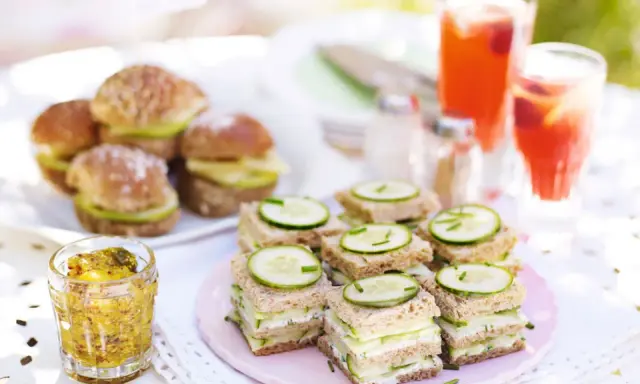 Små smörgåsar med gurka och ost, perfekta för ett afternoon tea recept. Serveras med röda drycker och senap.