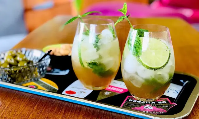 Två uppfriskande mojitos med mynta och lime, perfekt för ett somrigt mojito recept. Serveras med oliver på ett dekorativt fat.