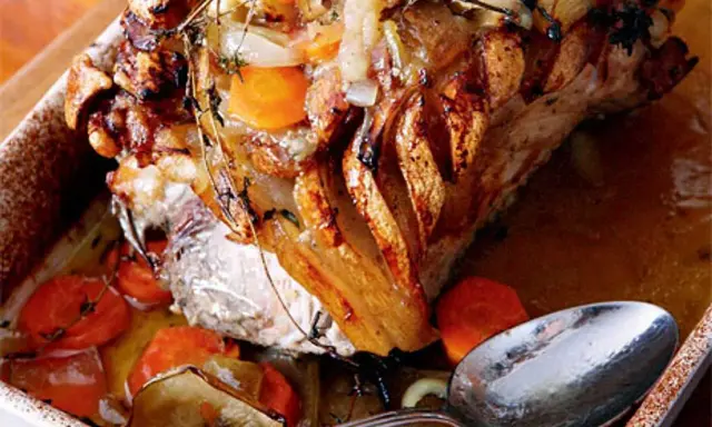 En saftig skinkstek med knaprig svål, serverad med rotfrukter och en sked redo att ösa. Ett perfekt skinkstek recept för helgen.