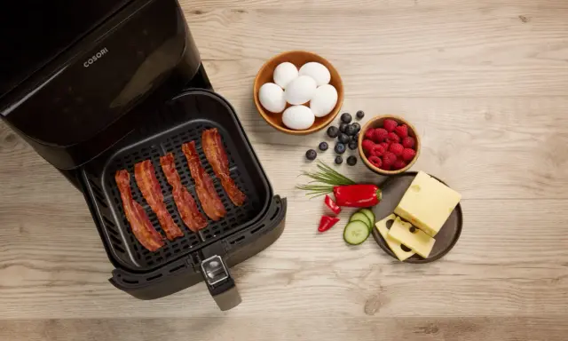 Krispigt bacon i airfryer, redo för en god frukost med ägg, bär och ost.
