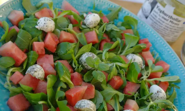 En uppfriskande sallad med vattenmelon, gröna blad och små bollar av ost, perfekt som sallad till paj.