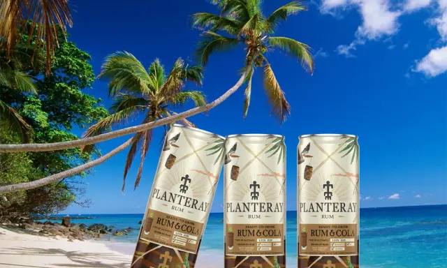 Tre burkar rom och cola står på en tropisk strand med palmer och blå himmel.