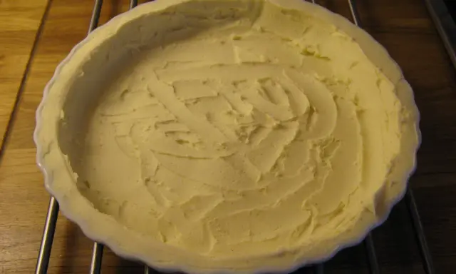 En vit pajform med en färdig glutenfri pajdeg från Lailas. Pajdegen är pressad mot formens kanter och har ett mönster i mitten.