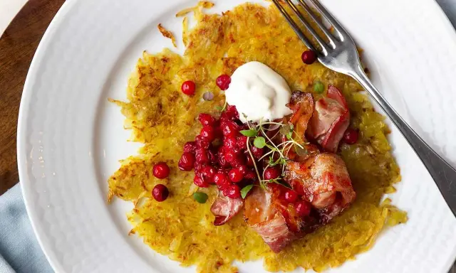 En gyllene råraka med knaperstekt bacon, lingon och en klick gräddfil. Ett klassiskt råraka recept som är perfekt för en helgmåltid.