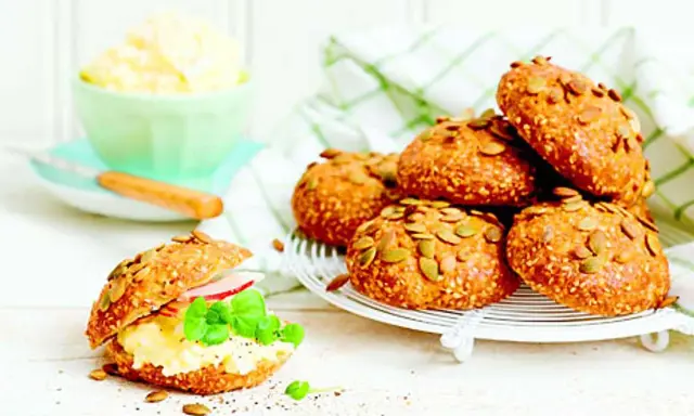 Frukost tips: Nybakade frallor med pumpafrön och sesamfrön, en fylld med äggsallad, skinka och basilika.
