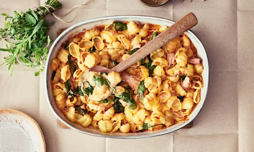 Enkel lyxig middag: krämig pastasås med snäckpasta, spenat och skinka i ugnsform. Serveras med färska örter.
