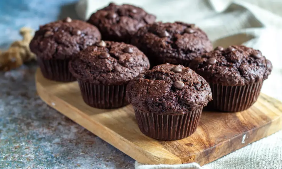 Fluffiga muffins recept: Mörka chokladmuffins med chokladknappar på en träbricka. Perfekta för fikat!