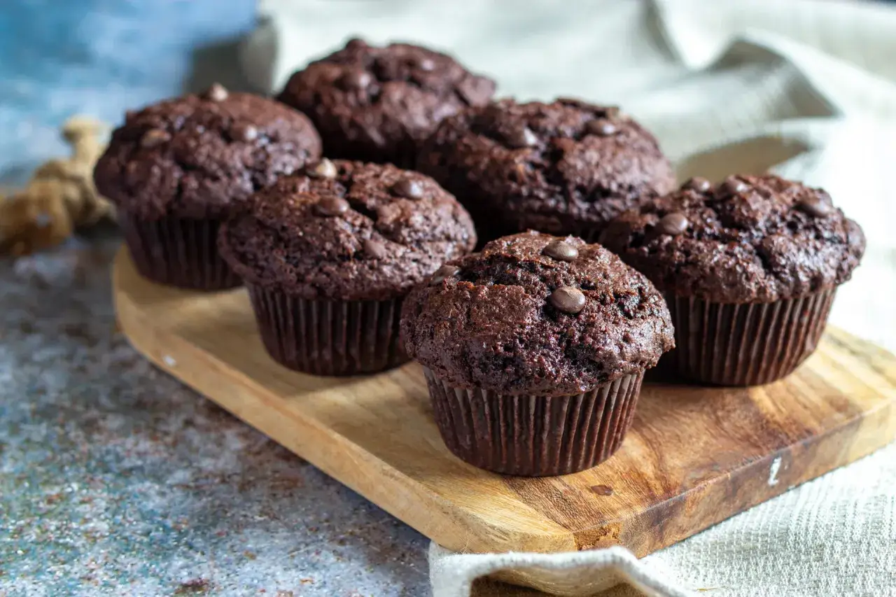 Fluffiga muffins recept: Mörka chokladmuffins med chokladknappar på en träbricka. Perfekta för fikat!