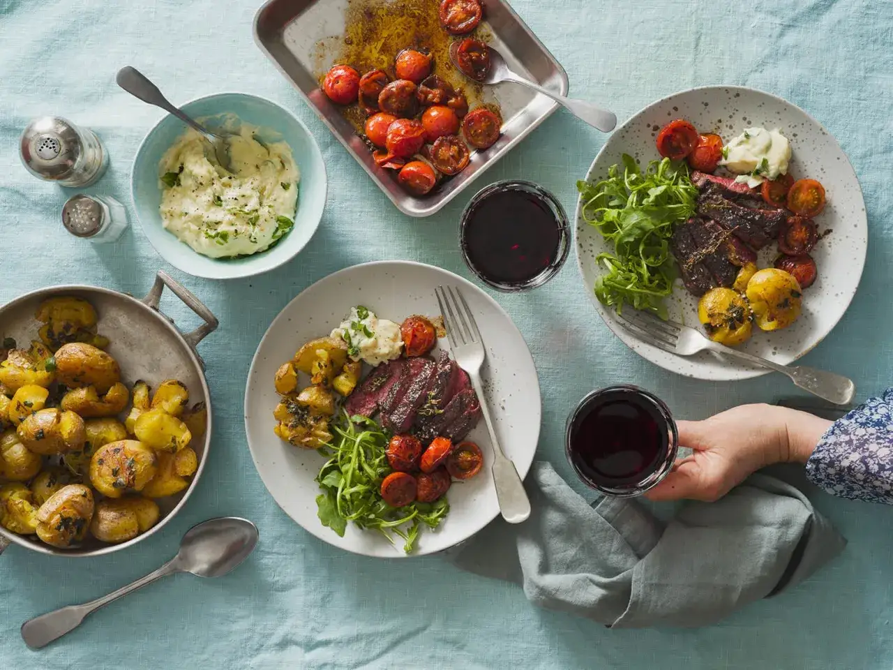 Tv&aring; tallrikar med saftig ryggbiff i ugn, serverad med ugnsrostade sm&aring;potatisar, k&ouml;rsb&auml;rstomater, potatismos och rucola. Ett glas r&ouml;dvin till varje portion.