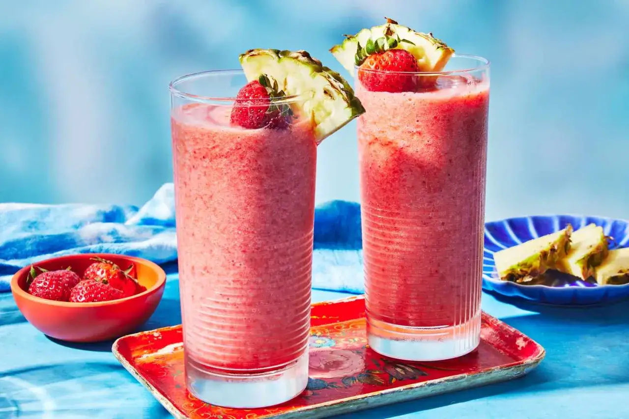 Två frostiga romdrinkar med jordgubbar och ananas, perfekta enkla drinkar med rom för en solig dag.