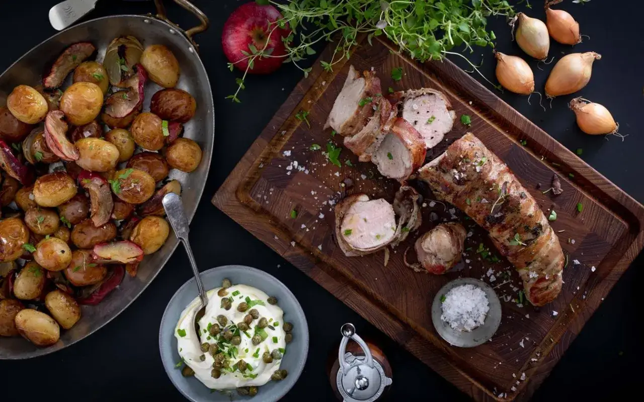En saftig ytterfile i ugn, insvept i bacon, serveras med ugnsrostade småpotatisar och en krämig sås med kapris.