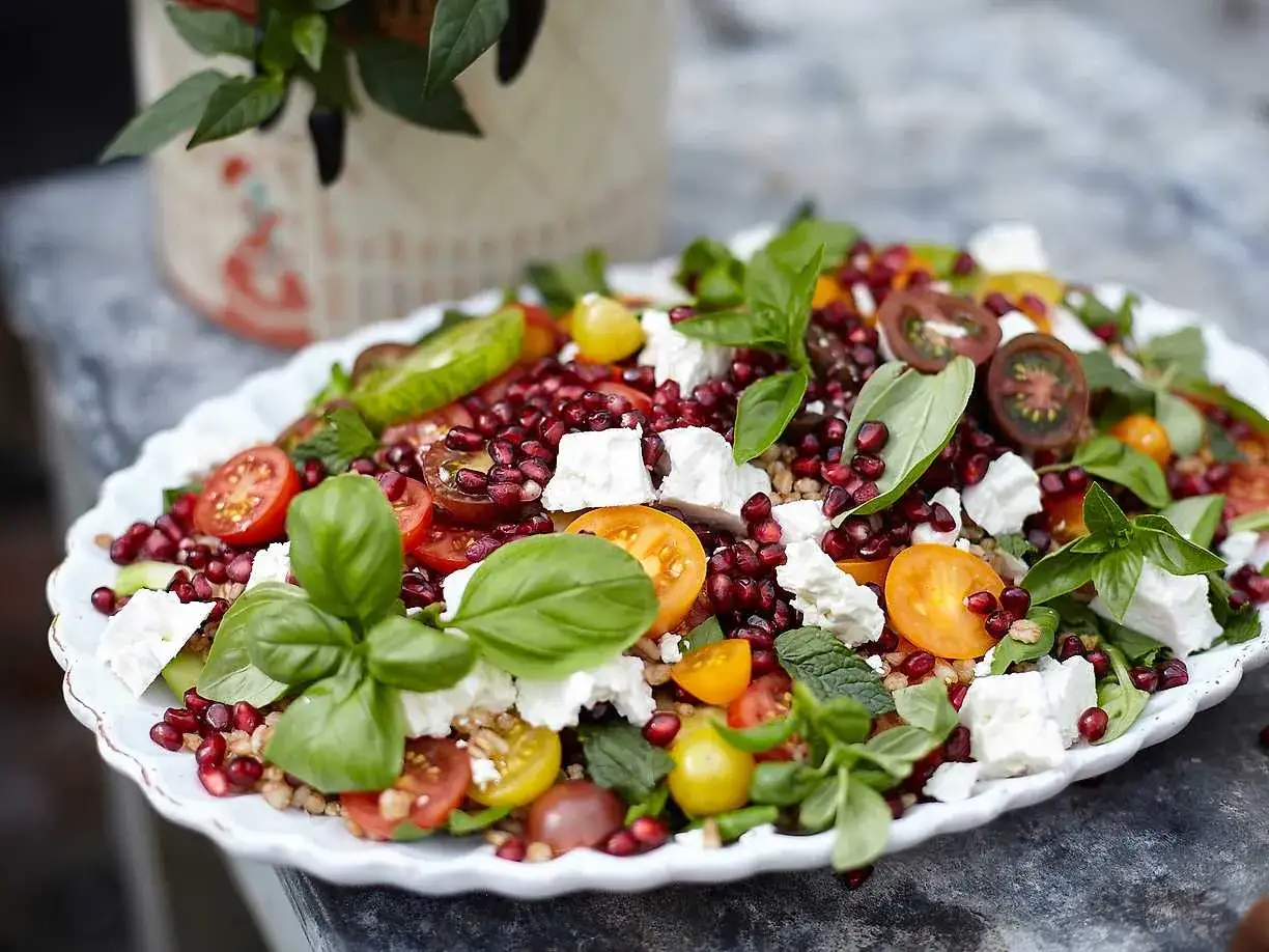 En färgglad sallad med granatäpple, tomater, fetaost och basilika, perfekt som sallad till paj.