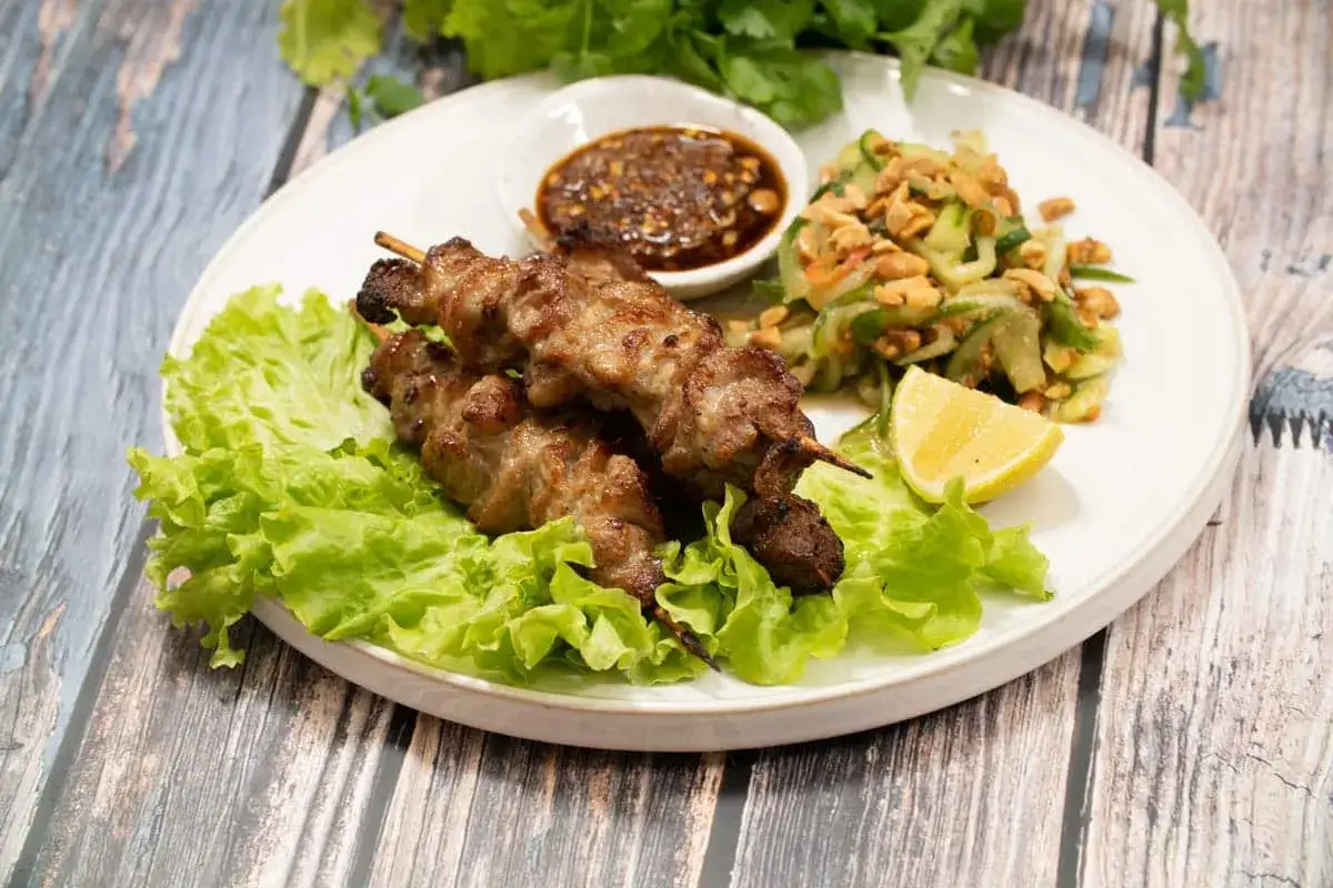 Grillspett recept: saftiga köttspett på salladsbädd med gurksallad, dippsås och citronklyfta.