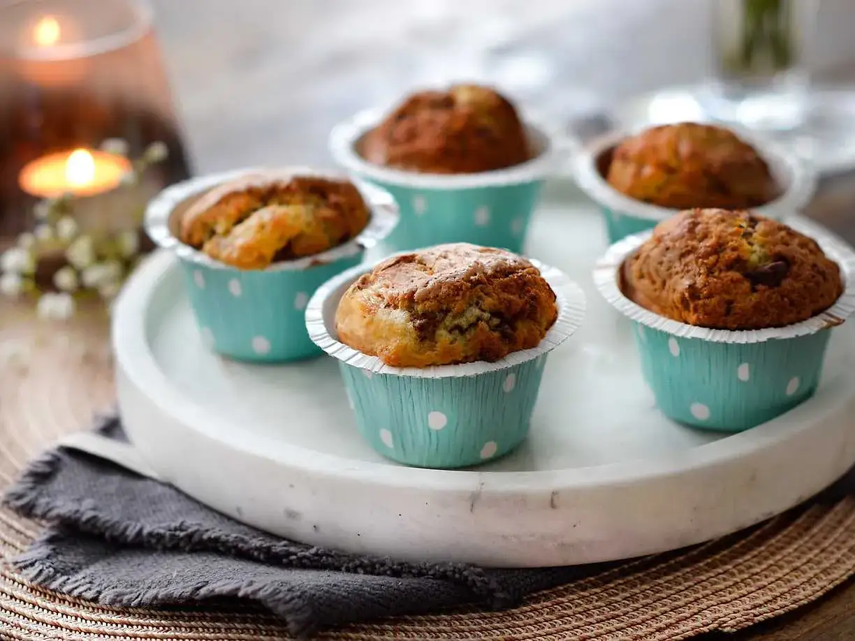 Nybakade muffins i ljusblåa pappersformar med prickar, perfekta att baka i airfryer för en snabb fika.