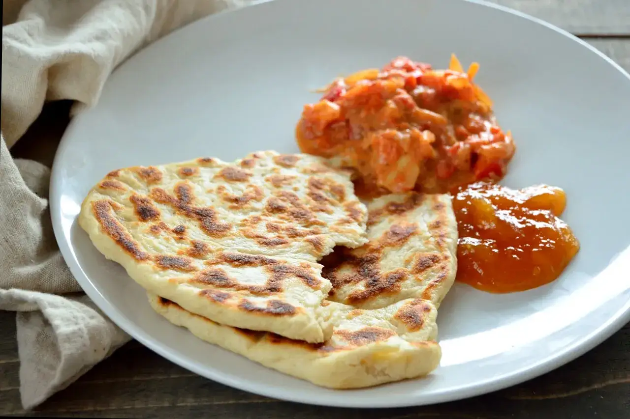 Två bitar naanbröd med en klick kryddig tomatsalsa och söt mango chutney. Perfekt tillbehör till indisk mat, kanske som en del av ett mango chutney recept.