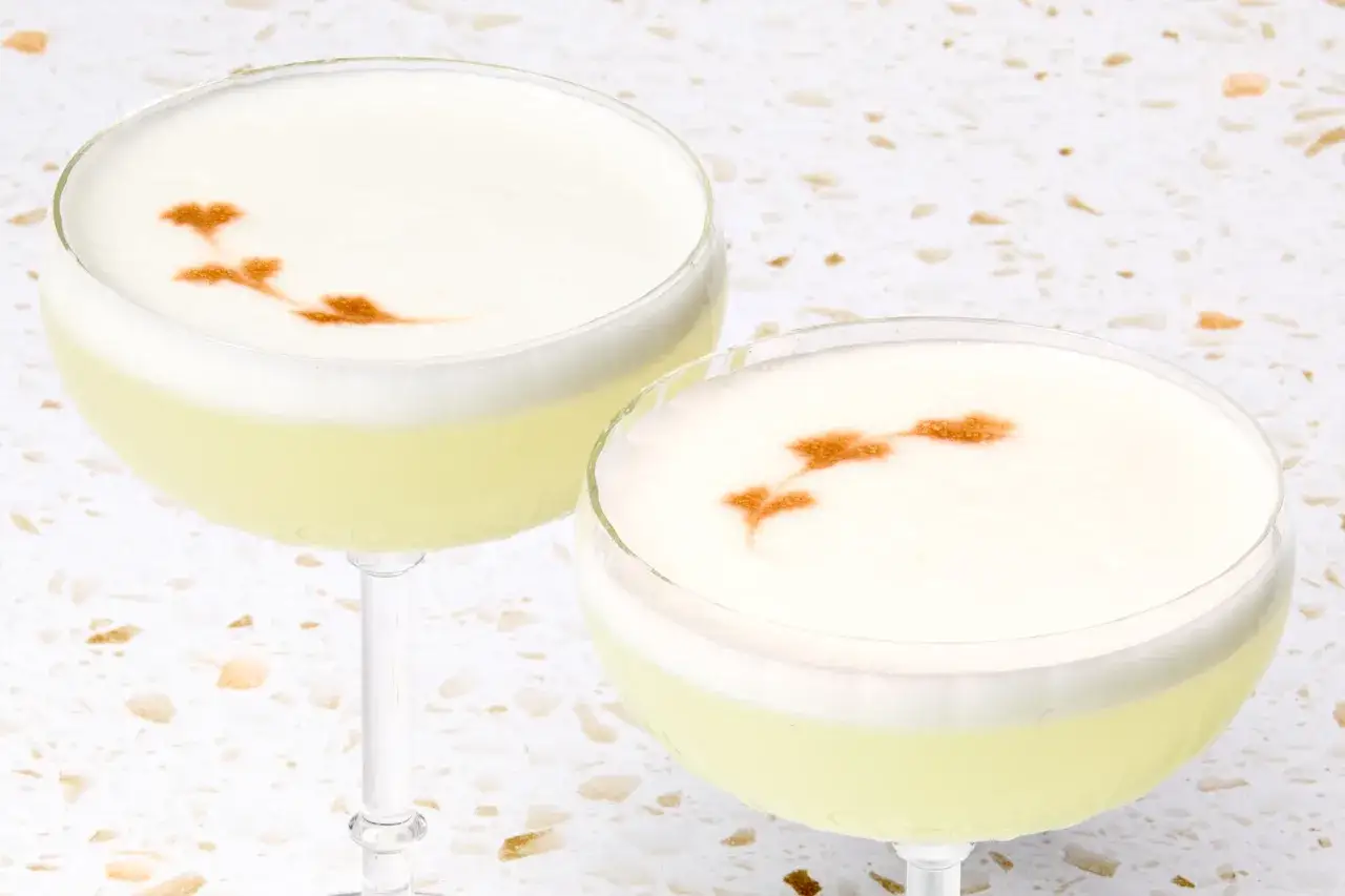 Två pisco sour-drinkar med skummig topp och en fin dekoration av kanel.
