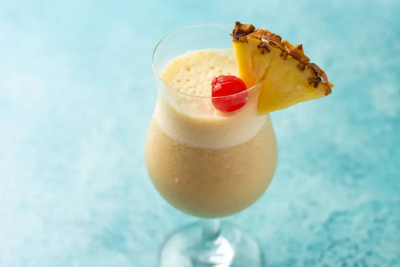 En kr&auml;mig virgin pi&ntilde;a colada med ananasskiva och k&ouml;rsb&auml;r, perfekt f&ouml;r en solig dag.