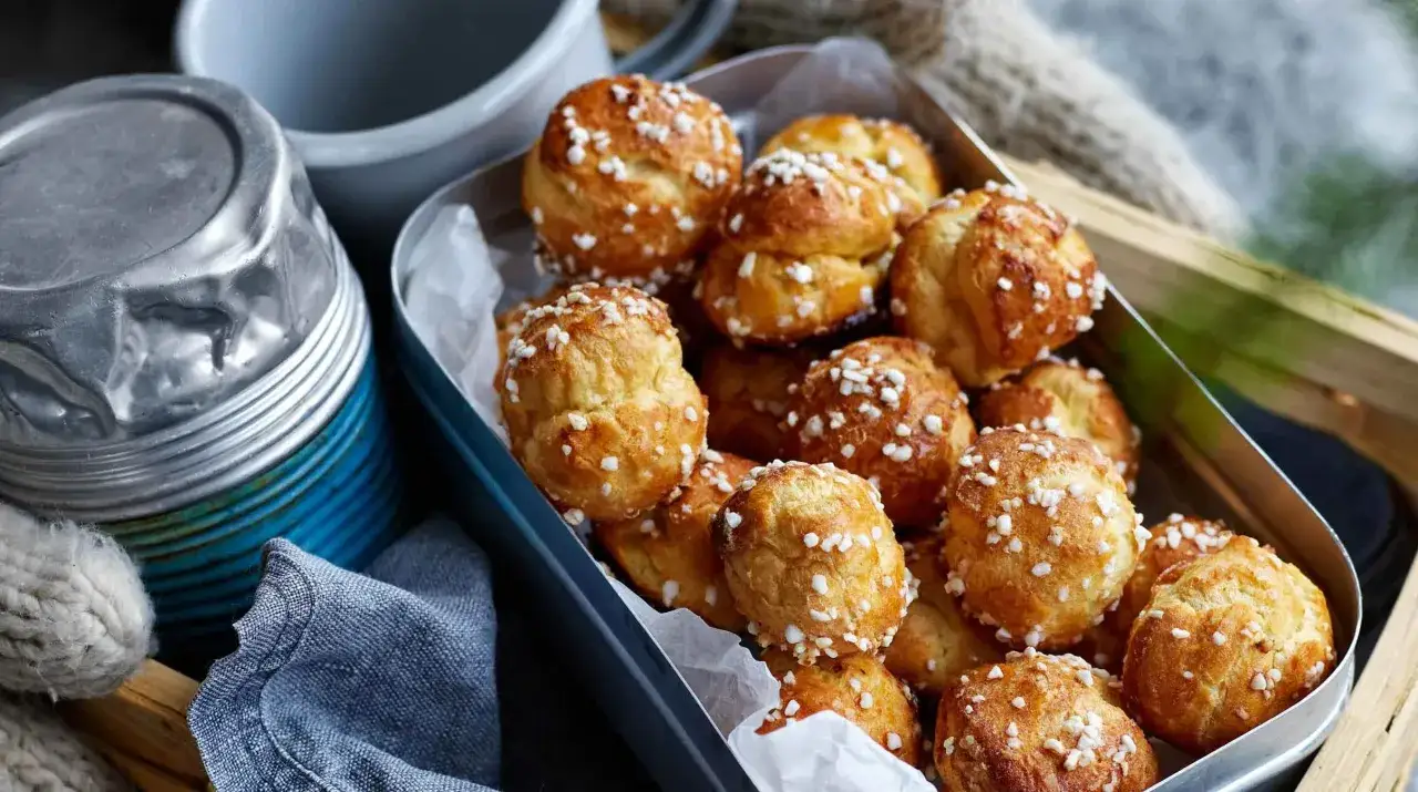 En låda med gyllene petit choux, strösslade med pärlsocker, redo att avnjutas.