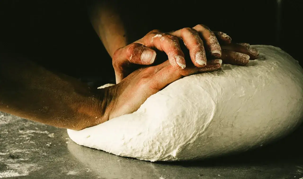 Händer knådar deg för en äkta napolitansk pizza.