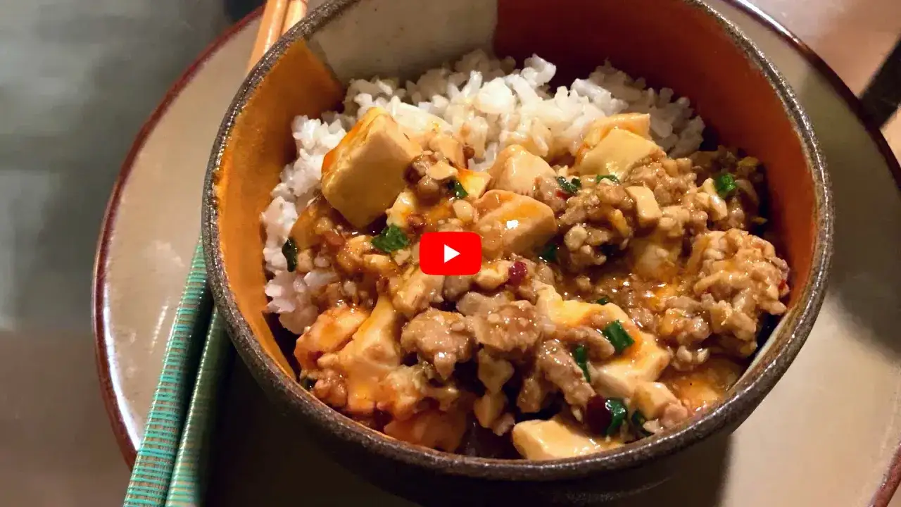 En skål med ris toppad med kryddig mapo tofu och köttfärs. En läcker asiatisk rätt.