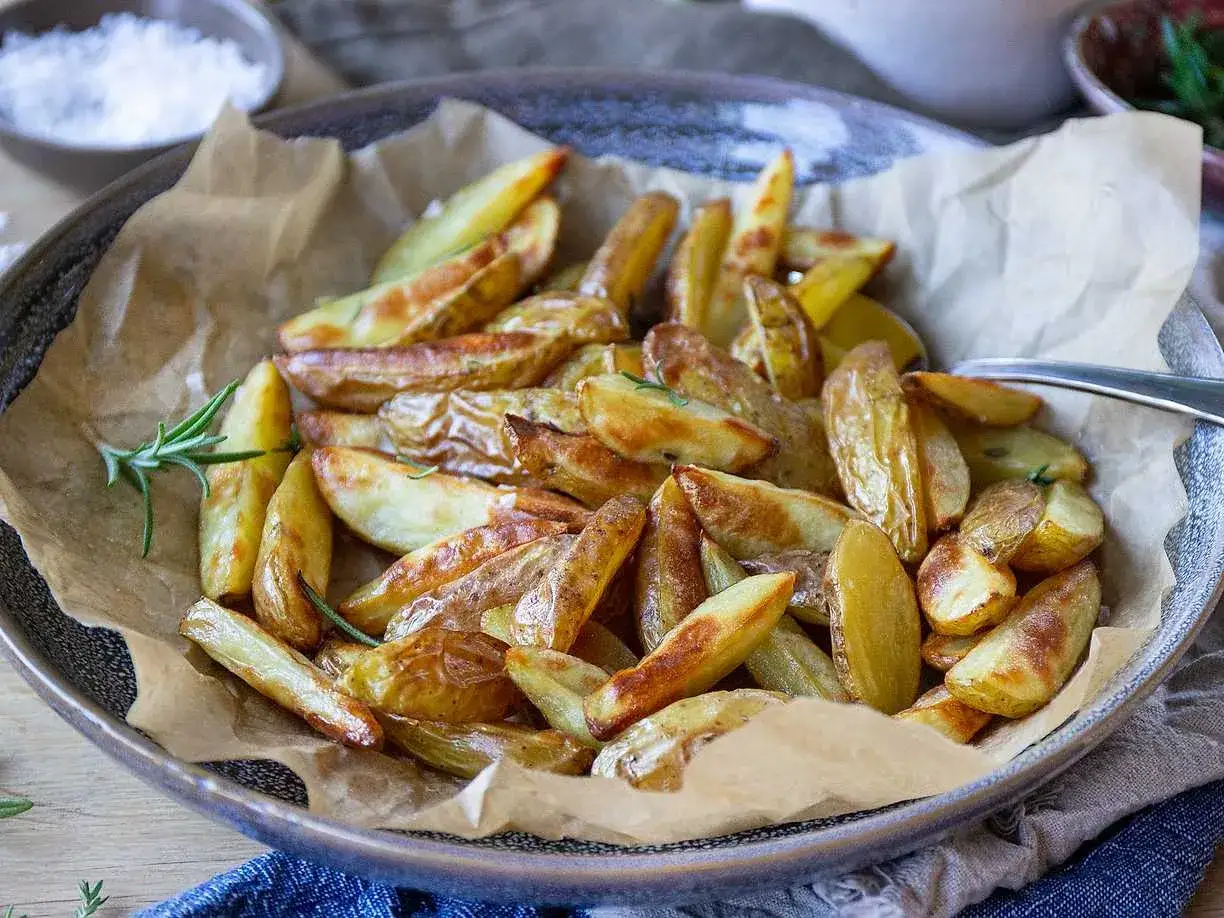Klyftpotatis i airfryer, gyllene och krispiga, serverade med f&auml;rsk rosmarin. Perfekt som tillbeh&ouml;r!