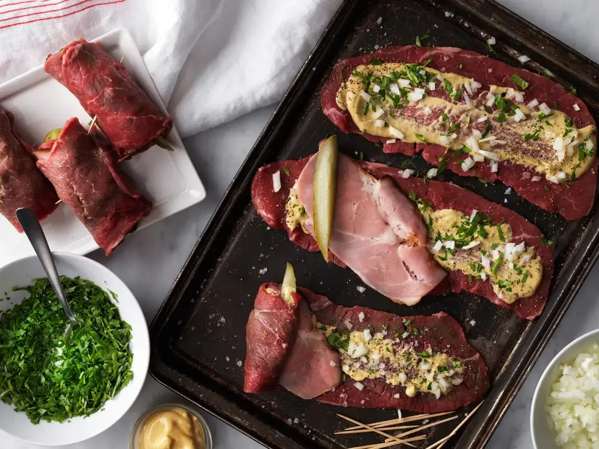 Råa innanlår rullas med senap, lök och skinka. Ett klassiskt innanlår recept förbereds.