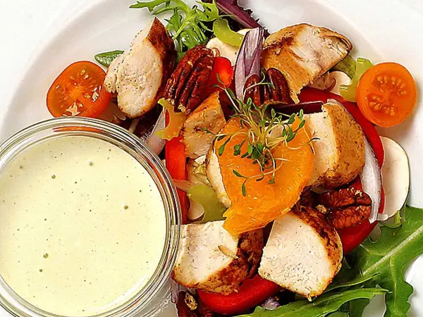 En härlig kycklingsallad med saftiga kycklingbitar, nötter, apelsin och en krämig dressing till kycklingsallad.